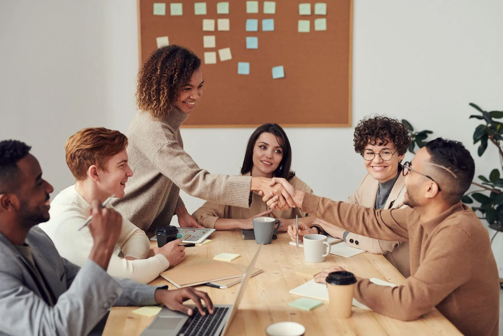 Grupo de adultos conversa en equipo alrededor de una mesa durante una reunión de apoyo
